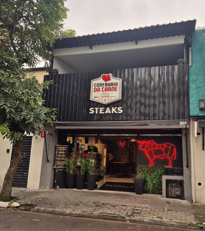 Fachada da Confraria da Carne na Rua Henri Dunant, 1014, com letreiro neon do touro